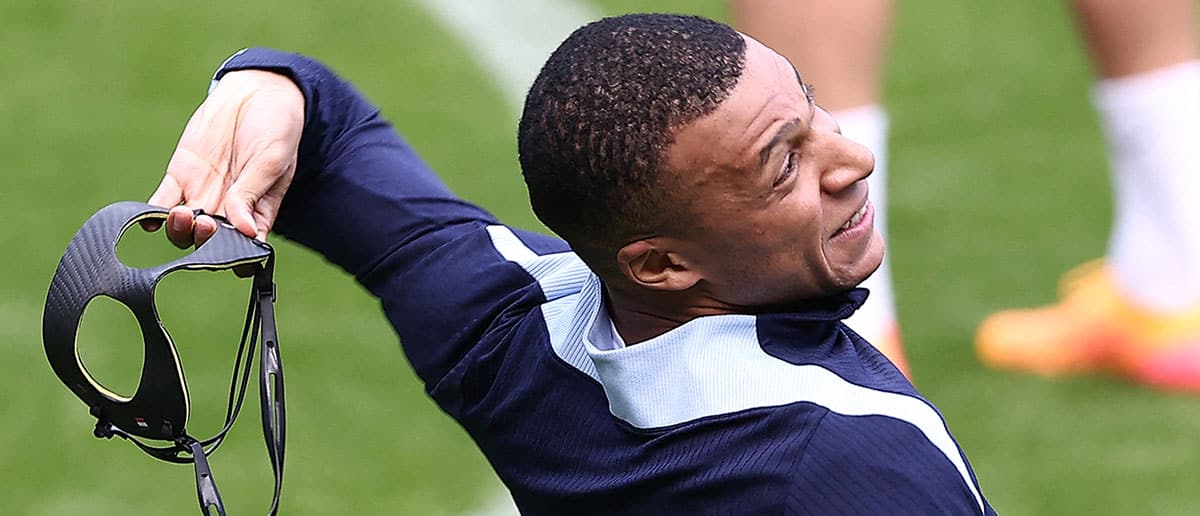 France's forward #10 Kylian Mbappe throws his protective face mask as he jokes during a training session within the UEFA Euro 2024 Football Championship at the Home Deluxe Arena Stadium in Paderborn, western Germany, on June 23, 2024.