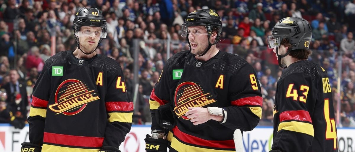 J.T. Miller #9 of the Vancouver Canucks talks to teammates Quinn Hughes #43 and Elias Pettersson #40 during their NHL game against the Arizona Coyotes at Rogers Arena on April 10, 2024 in Vancouver, British Columbia, Canada.