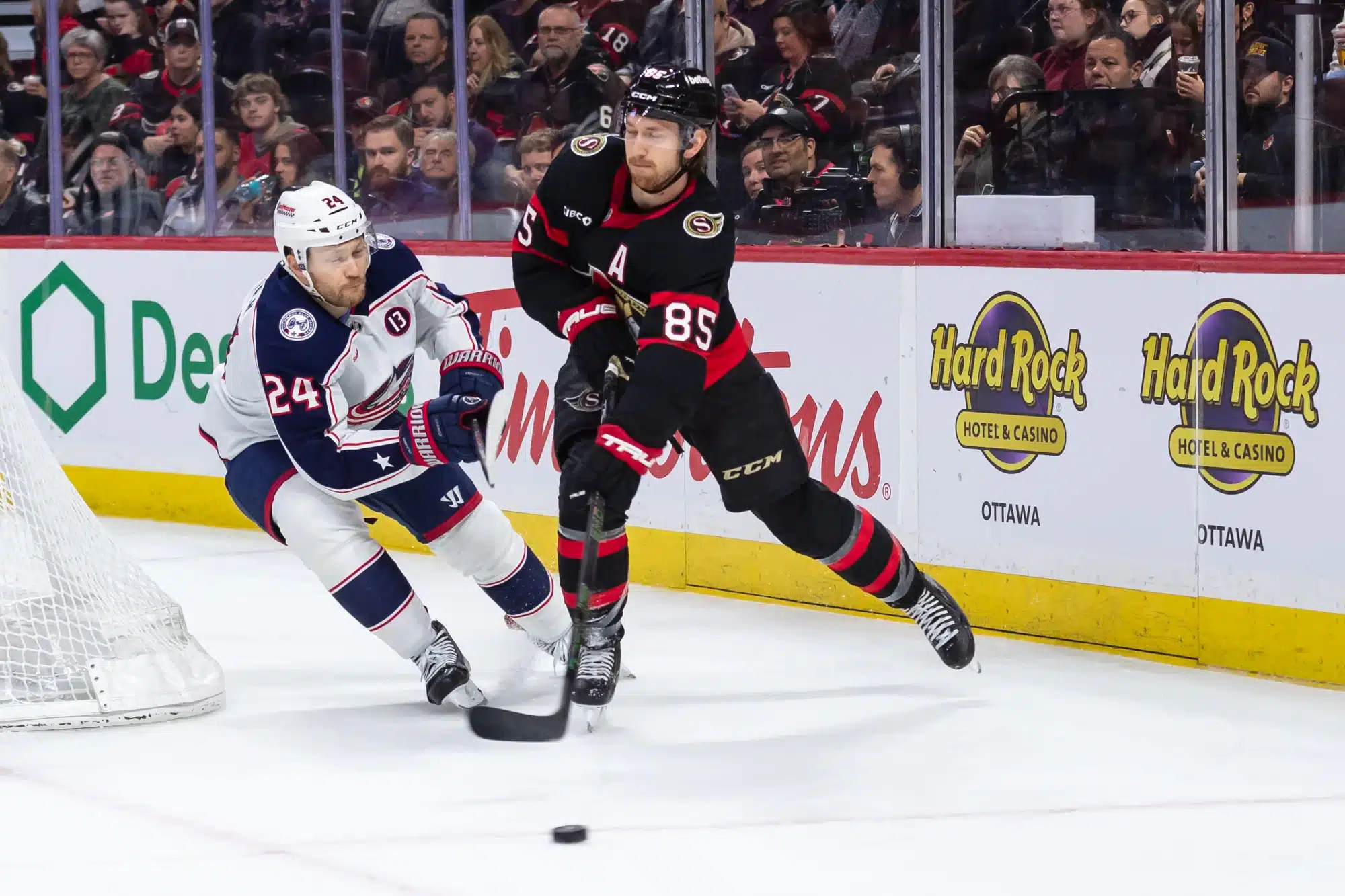 Apr 6, 2025; Ottawa, Ontario, CAN; Columbus Blue Jackets right wing Mathieu Olivier (24) chases Ottawa Senators defenseman Jake Sanderson (85) as he shoots the puck in the second period at the Canadian Tire Centre. 
